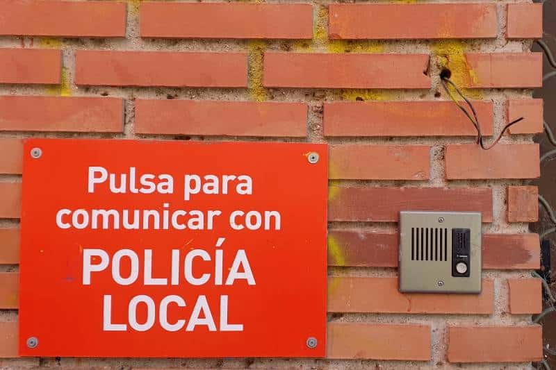 Detalle del interfono y el cartel informativo en el exterior del local cerrado de Policía Local en Covibar